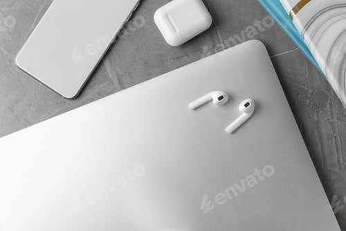 Preview: Flat lay composition with wireless earphones and laptop on grey stone table