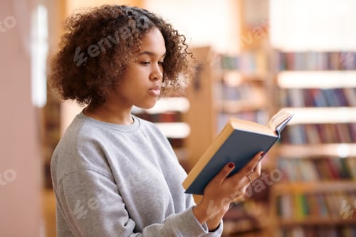 Preview: Pretty college student in casualwear reading interesting book