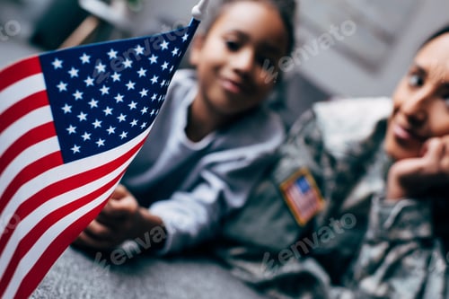 Preview: african american daughter and mother in military uniform with american flag at home