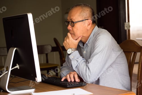Preview: Asian businessman sitting and looking at computer in the office room.