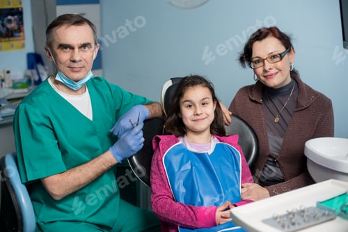 Preview: Girl with on the first dental visit. Senior pediatric dentist with mother treating patient teeth
