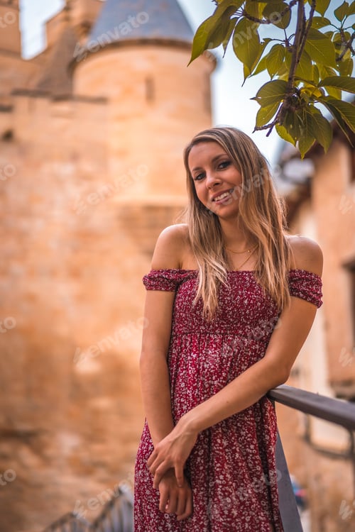Preview: Portrait of a blonde woman next to a medieval castle in a red dress