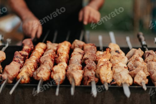 Preview: Frying shish kebab on the skewers in brazier. Fresh ruddy meat for barbecue grill on fire outdoor.