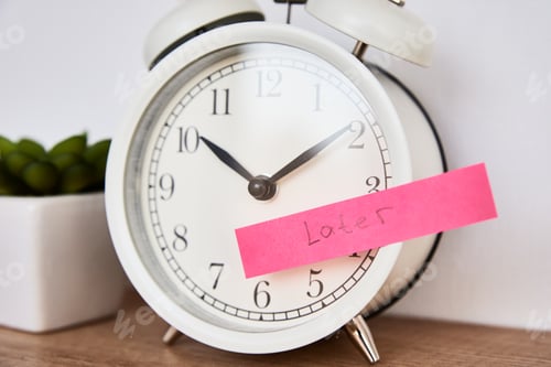 Preview: Procrastination and delay concept. Sticky note with word later on white alarm clock. Urgency time