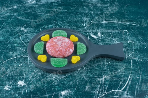 Preview: A cookie surrounded with marmelades on a small serving pan on blue background