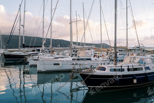 Preview: Marina with yachts at the foot of the mountains in the evening in sunset reflections