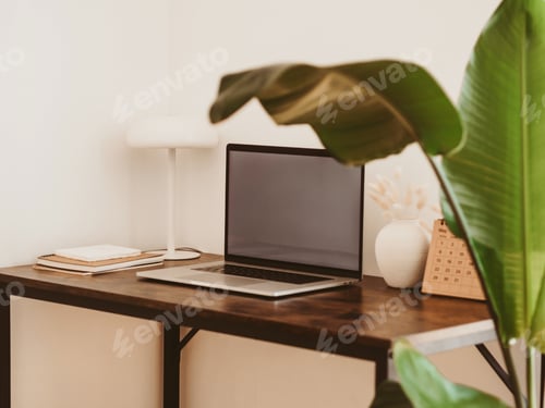 Preview: Laptop with blank screen on wooden table in home interior.