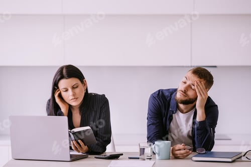 Preview: Focused woman and tired man at office desk with laptop and notes