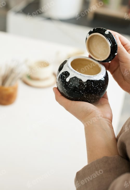 Preview: Female artist holding handmade pottery at a studio
