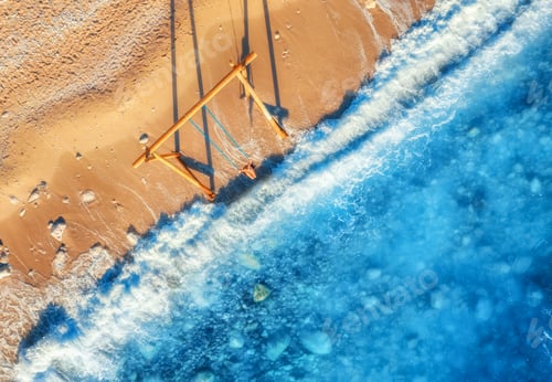 Preview: Aerial view of woman on the swing, beautiful blue sea with waves