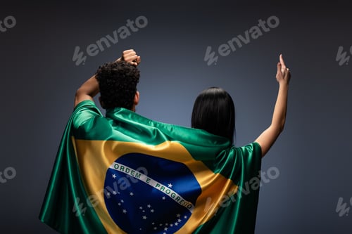 Preview: couple of football fans gesturing with brazil flag on grey