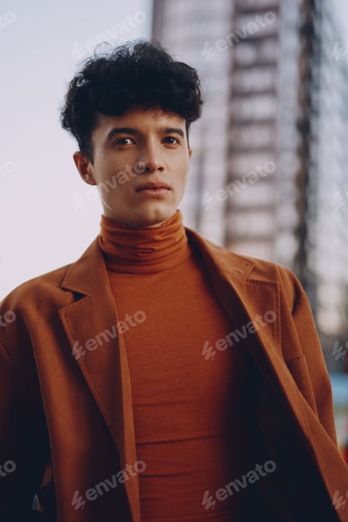 Vista previa: Portrait of a young man in a stylish orange outfit against a modern urban background