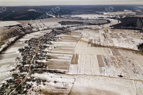 Preview: Top view of empty snowy fields, houses along road and woody hills