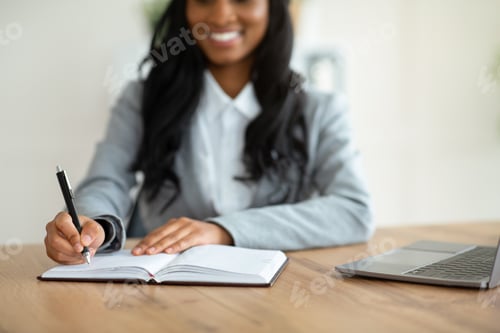 Preview: Unrecognizable black female secretary writing down info during online business meeting at workplace