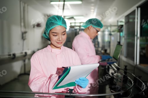 Preview: worker controlling the work of machine in production line at beverage industry.