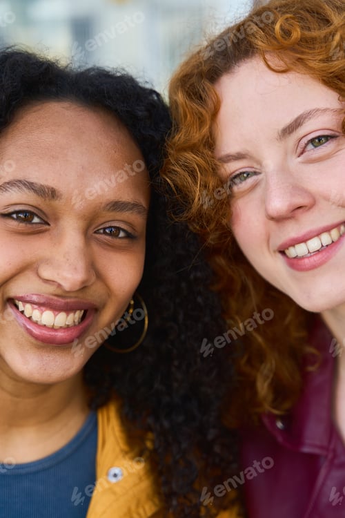 Preview: Two young women smiling and embracing diversity outdoors