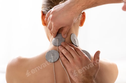 Preview: Therapist fastening electrodes on neck of patient during electrotherapy isolated on white