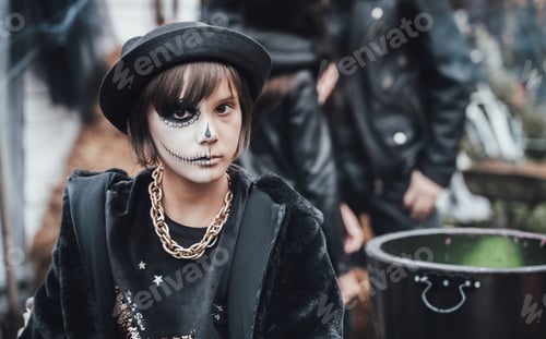 Preview: Beautiful scary little girl celebrating halloween. Terrifying black, white half-face makeup and witc