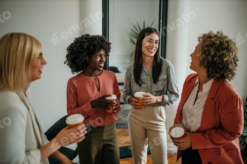 Preview: Businesswomen enjoying coffee break, chatting and smiling in office