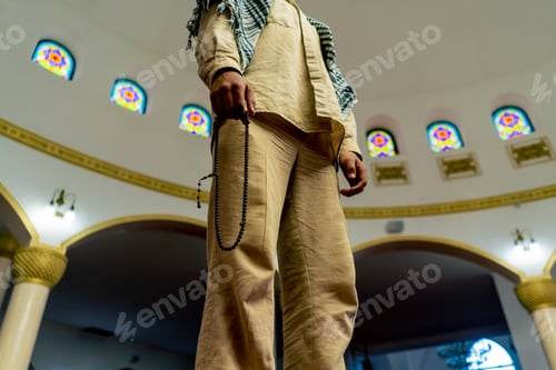 Preview: Muslim man stands on the carpet in the middle of the prayer hall at mosque with his head raised up