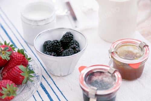 Preview: Summer fruits in bowls and preserves in jars on tablecloth