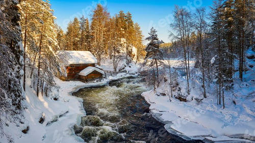 Preview: Wild river streaming through snowy forest near cozy house