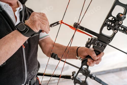 Preview: Closeup, selective focus of professional archer preparing bow and arrow for training
