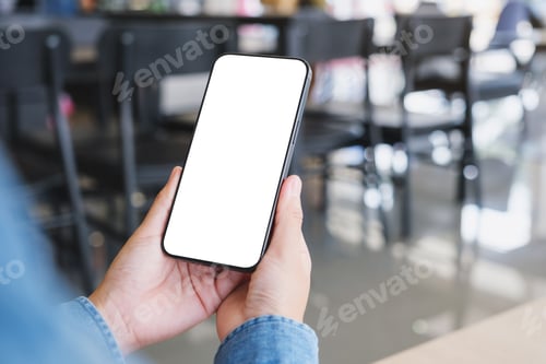 Preview: Mockup image of a woman holding and using mobile phone with blank desktop in cafe
