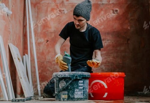 Preview: A young man is holding a bottle of detergent and a sponge.
