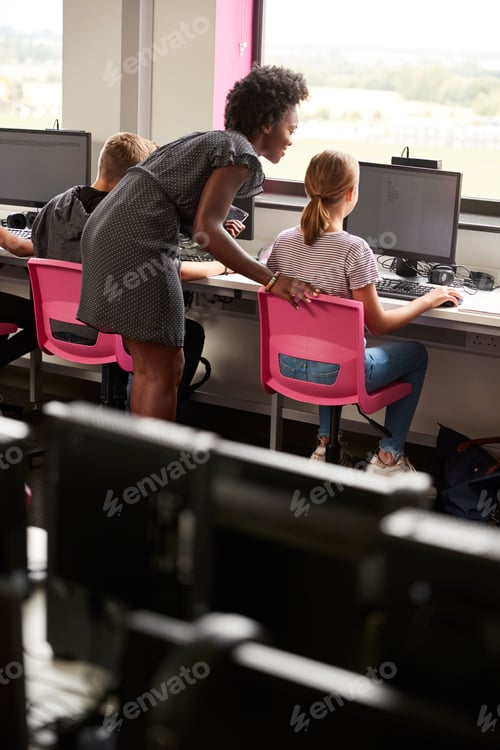Preview: Teacher Helping Female Pupil Line Of High School Students Working at Screens In Computer Class