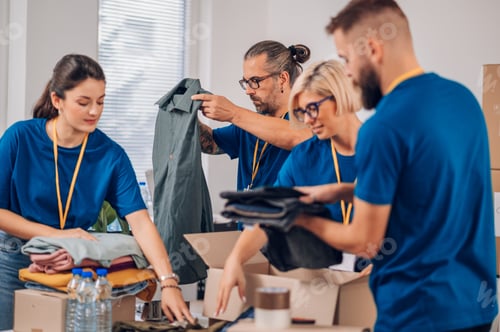 Preview: Diverse volunteers working in a charity donation center and packing clothes and food