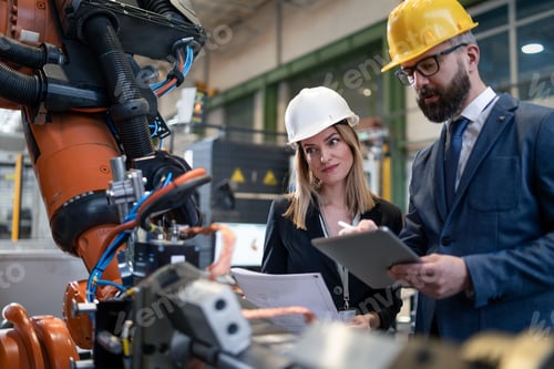 Preview: Chief engineer and project manager in modern industrial factory with robot arms talking and planning
