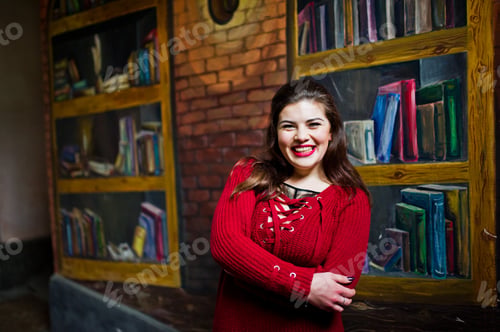Preview: Brunette plus size model against wall like library.