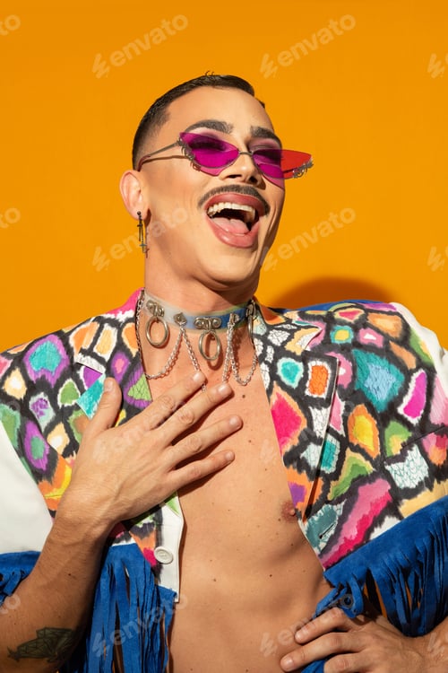 Preview: Portrait of happy young drag queen laughing in a colorful dress on a yellow background
