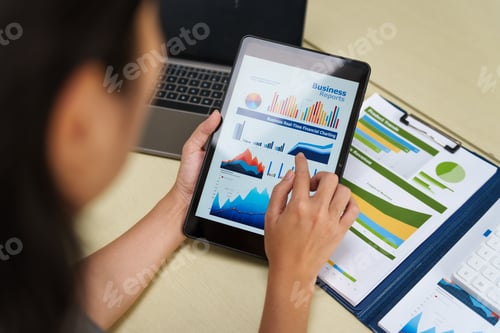 Preview: housewife in a grey t-shirt works from home at a desk with a whiteboard, managing financial tasks