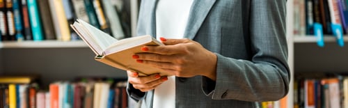 Preview: panoramic shot of woman holding book while standing in library