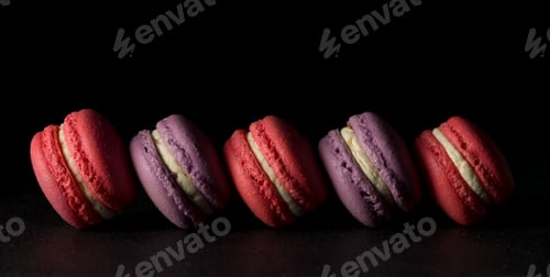 Preview: Colored macaroons. Delicious sweet colorful French desserts on black background