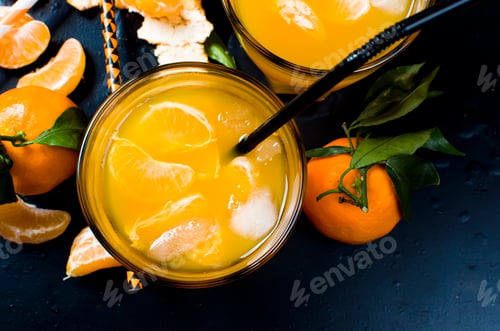 Preview: refreshing cocktail with tangerine, juice and ice in two glasses on black background,