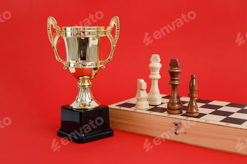 Preview: Winner golden cup and Chess board with wooden figures still life on red background