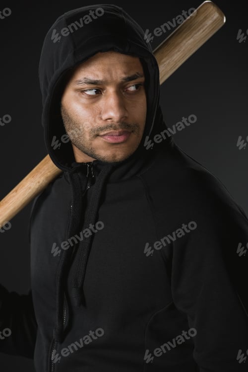 Preview: young african american robber in zoodie with baseball bat isolated on black