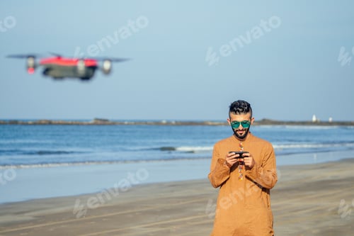Preview: arabian man testing a drone photo and video shooting on quadrocopter over the sea in Goa beach