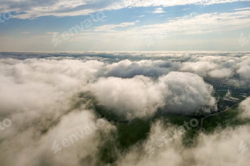 Preview: Aerial view of white clouds above a town or village with rows of buildings and curvy streets between