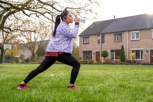Preview: Healthy woman stretching listening to music at the public park