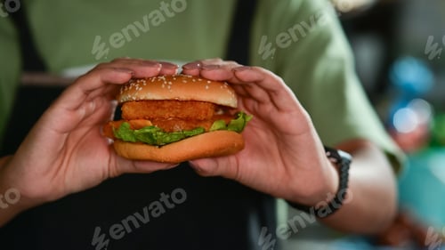 Preview: Woman holding tasty homemade fish burger.