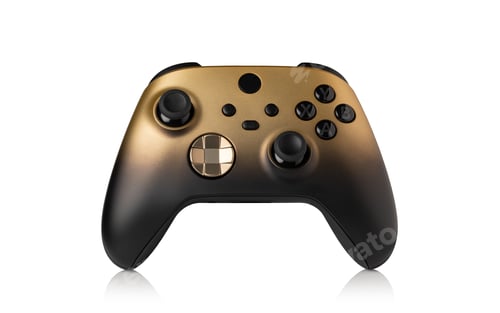 Preview: Black and gold video game controller resting on white background