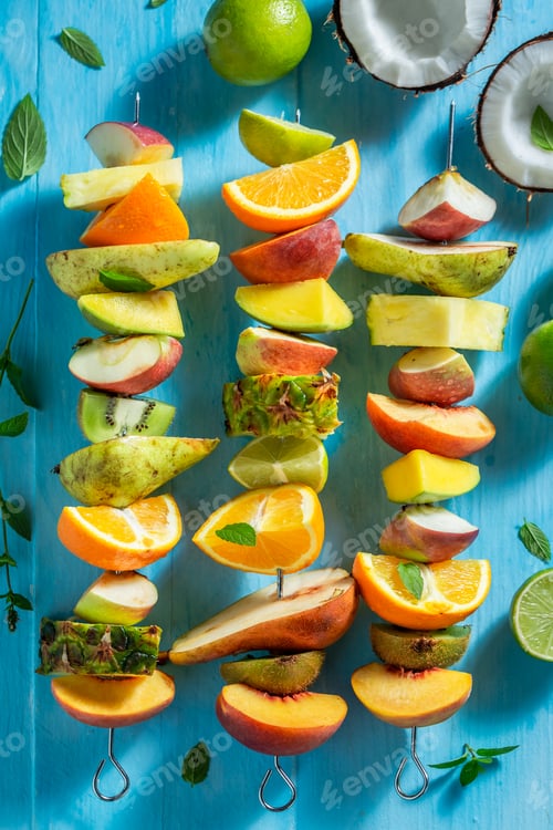 Preview: Top view of sweet skewers with fruits on blue table