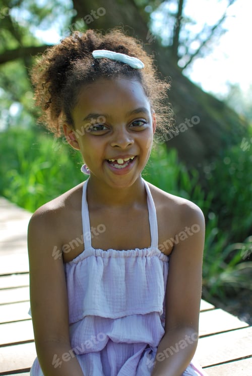 Preview: Girl of mixed race wearing summer dress and sitting on wood bridge - countryside portrait