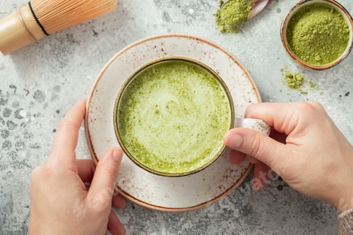Preview: Green matcha tea powder with spoon on white concrete background.