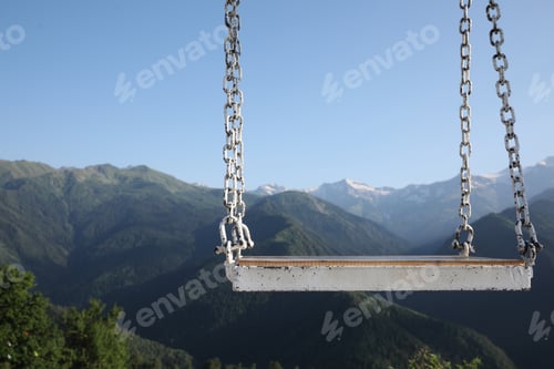Preview: Outdoor metal swing in beautiful mountains on sunny day, space for text