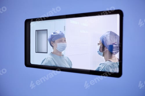 Preview: Window view of two female surgeons having discussion in maternity ward operating theatre